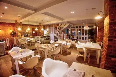 a restaurant with tables and chairs in a room at Seckford Hall Hotel & Spa in Woodbridge