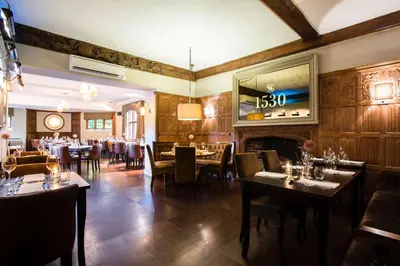 a restaurant with tables and chairs and a fireplace at Seckford Hall Hotel & Spa in Woodbridge