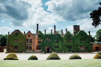 a large brick building with ivy growing on it at Seckford Hall Hotel & Spa in Woodbridge