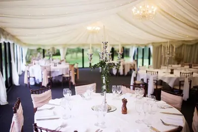 a banquet room with tables with white tablecloths and chairs at Seckford Hall Hotel & Spa in Woodbridge