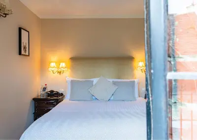 a bedroom with a bed with blue pillows and a window at Seckford Hall Hotel & Spa in Woodbridge