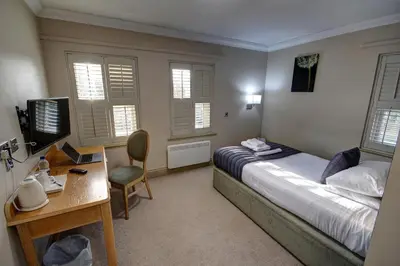 a bedroom with a bed and a desk with a computer at The Rochford Hotel in Southend-on-Sea