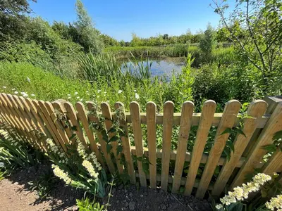 a wooden fence in front of a pond at White House Lodges in Heveningham