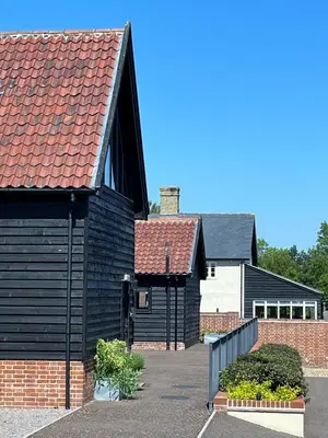 a black house with a red roof at White House Lodges in Heveningham