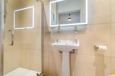 a bathroom with a sink and a mirror and a shower at White House Lodges in Heveningham