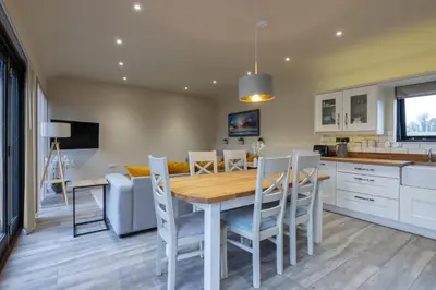 a kitchen and dining room with a wooden table and chairs at White House Lodges in Heveningham