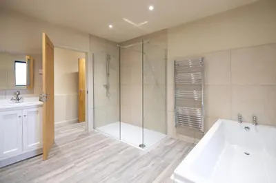 a bathroom with a shower and a tub and a sink at White House Lodges in Heveningham