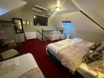 a bedroom with two beds and a table and a sink at Cambridge Bed & Breakfast in Cambridge