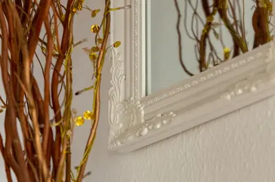 a mirror on a wall next to a vase with flowers at Cambridge Bed & Breakfast in Cambridge