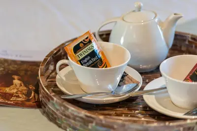 a tray with cups and saucers and a tea pot at Cambridge Bed & Breakfast in Cambridge