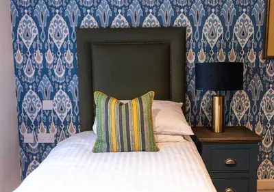 a bed with a pillow and a night stand with a lamp at Great Hallingbury Manor & Lodges London Stansted in Bishops Stortford