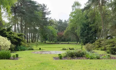 a garden with a pond and trees in the background at Great Hallingbury Manor & Lodges London Stansted in Bishops Stortford