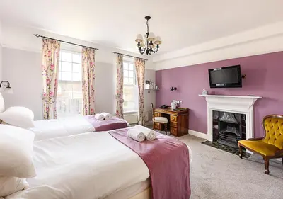 a bedroom with two beds and a fireplace at Sherbourne House in Attleborough