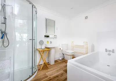a white bathroom with a shower and a sink at Sherbourne House in Attleborough