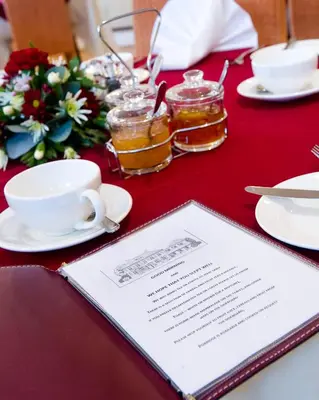 a table with a red table cloth with a menu and drinks at Sherbourne House in Attleborough