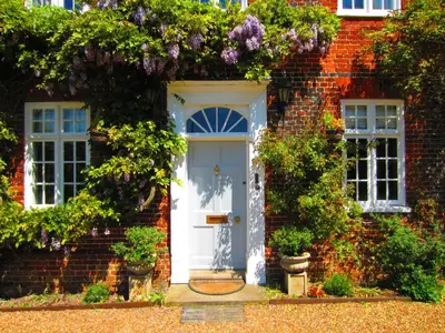 a brick house with a white door and flowers at Sherbourne House in Attleborough