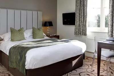 a hotel room with a bed and a desk and a window at Pontlands Park Hotel in Chelmsford