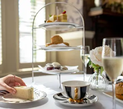 a table with plates of food and a person holding a piece of cake at Pontlands Park Hotel in Chelmsford