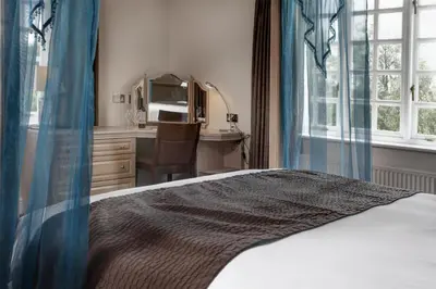 a bedroom with a bed and a desk and a kitchen at Ivy Hill Hotel, BW Signature Collection in Chelmsford