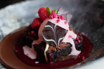 a piece of chocolate cake with strawberries on a plate at J.D.Young in Harleston