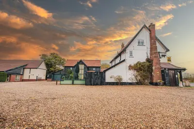 a house on a gravel field with a cloudy sky at The Auberge in Yaxley
