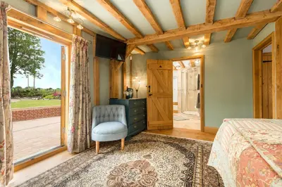 a bedroom with a bed and a chair and a window at Corner Farm in Halesworth