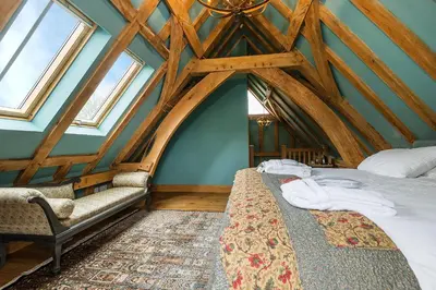 a room with a bed and a couch and windows at Corner Farm in Halesworth