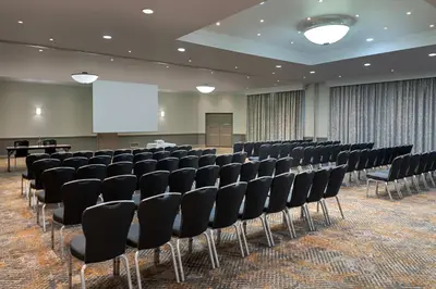 a conference room with black chairs and a white screen at Delta Hotels by Marriott Waltham Abbey in Waltham Abbey
