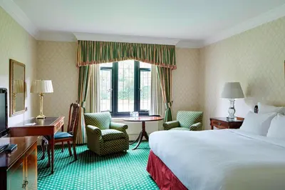 a hotel room with a bed and a table and chairs at Hanbury Manor Marriott Hotel & Country Club in Ware