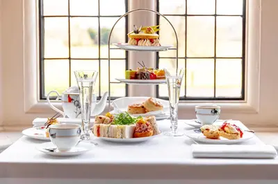 a white table with plates of food on it at Hanbury Manor Marriott Hotel & Country Club in Ware