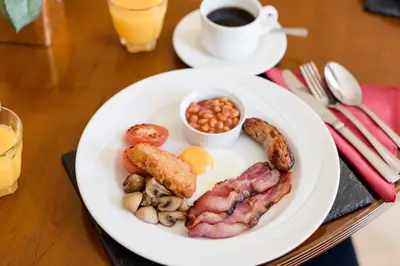 a plate of breakfast food on a table with a cup of coffee at Hinxton Hall Hotel and Conference Centre in Hinxton