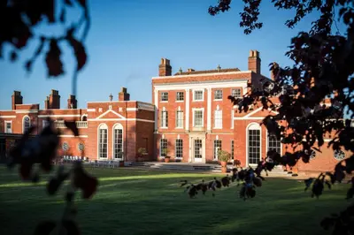 a large brick building with a grass field in front of it at Hinxton Hall Hotel and Conference Centre in Hinxton