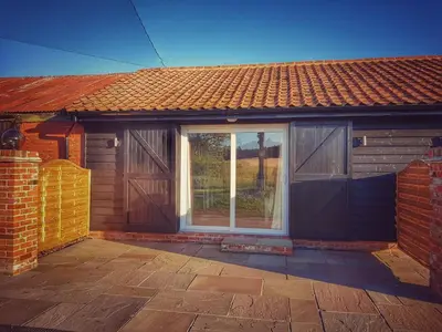 a brick house with a door and a patio at Plumptons Farm Holiday Lodges in Colchester