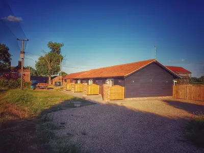 a building with a fence next to a house at Plumptons Farm Holiday Lodges in Colchester