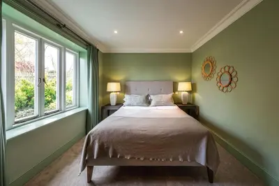 a green bedroom with a bed and two windows at The Crown Inn in Stoke by Nayland