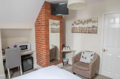 a bedroom with a brick fireplace and a chair at Toothbrush Rooms at Lattice Lodge - Guest Kitchen & EV Recharging in Ipswich