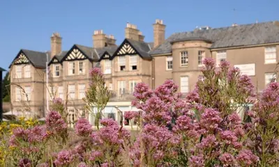 a large building with pink flowers in front of it at Wentworth Hotel in Aldeburgh