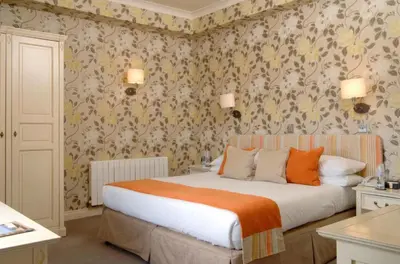 a bedroom with a large bed with floral wallpaper at Wentworth Hotel in Aldeburgh