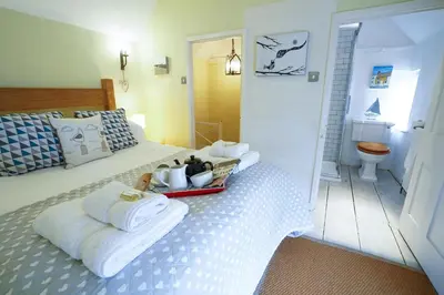 a bedroom with a bed with towels and a toilet at Aldeburgh Cottage in Aldeburgh
