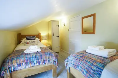 a bedroom with two beds and a mirror on the wall at Aldeburgh Cottage in Aldeburgh