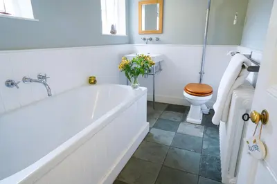 a white bathroom with a tub and a toilet at Aldeburgh Cottage in Aldeburgh