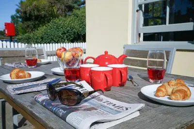 a wooden table with food and glasses and croissants at 1 South Cottages in Thorpeness
