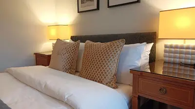 a bedroom with a bed with pillows and two lamps at Stansted Lodge Elsenham in Elsenham
