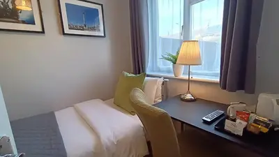 a hotel room with a bed and a desk and a window at Stansted Lodge Elsenham in Elsenham