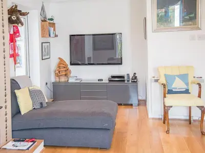 a living room with a couch and a flat screen tv at Honeybee Cottage, Orford in Orford