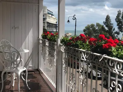 a balcony with red flowers and a table and chair at Pier View Self Catering Luxury Apartments in Southend-on-Sea