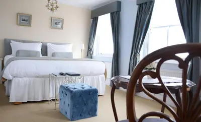 a bedroom with a bed and a chair and a window at Pier View Self Catering Luxury Apartments in Southend-on-Sea