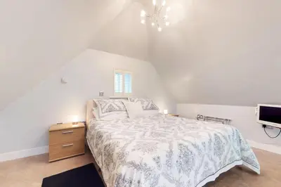 a white bedroom with a bed and a tv at Panfield House in Braintree
