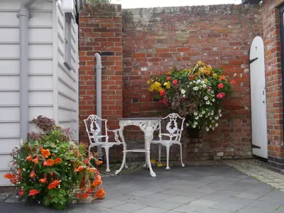 a patio with two white chairs and flowers at Panfield House in Braintree