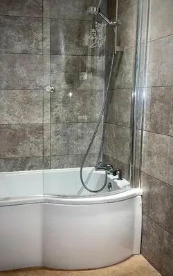a bathroom with a shower and a bath tub at Sibton White Horse Inn in Saxmundham